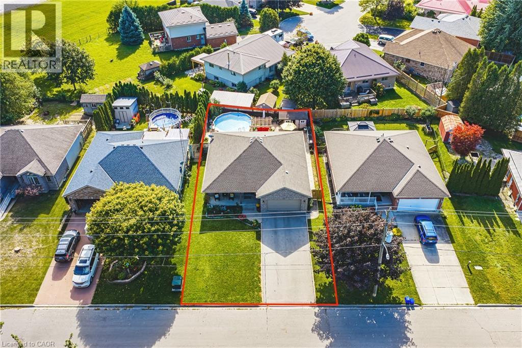 Expansive property featuring a gabled roof, attached garage, well-maintained lawn, paved driveway, and mature landscaping - 915 St George Street, Port Dover, ON