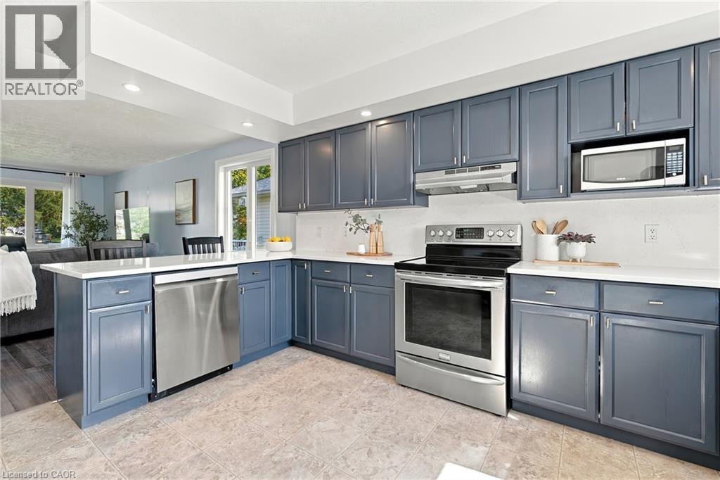Kitchen featuring blue shaker-style cabinetry, stainless steel appliances, white countertops, and tile flooring - 915 St George Street, Port Dover, ON