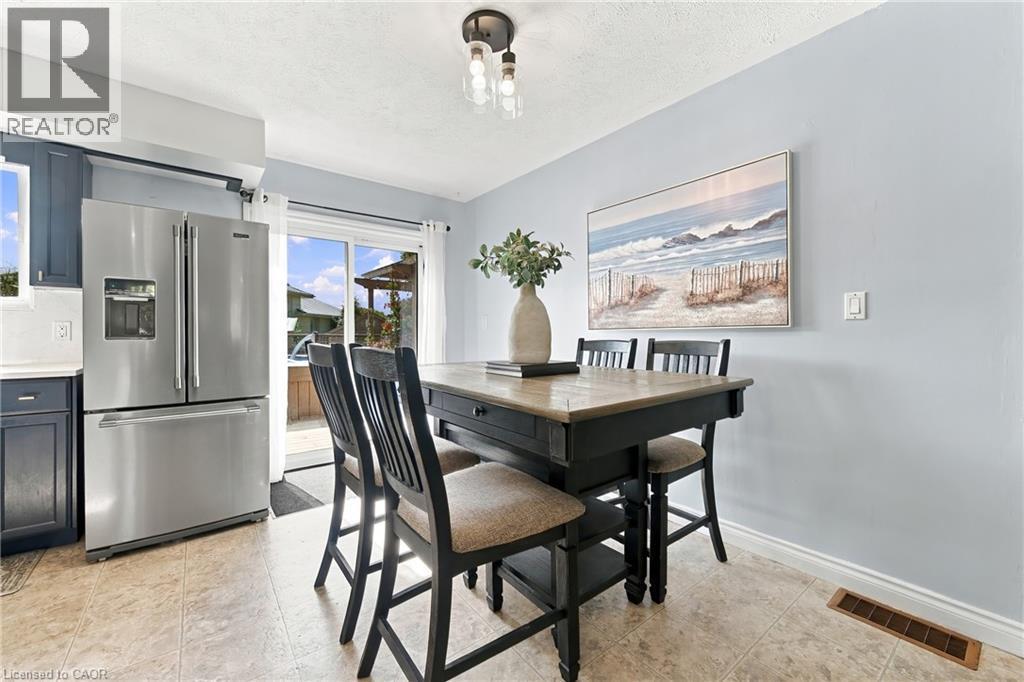 Stainless steel refrigerator, built-in cabinetry, tiled flooring, overhead lighting, and sliding glass door - 915 St George Street, Port Dover, ON