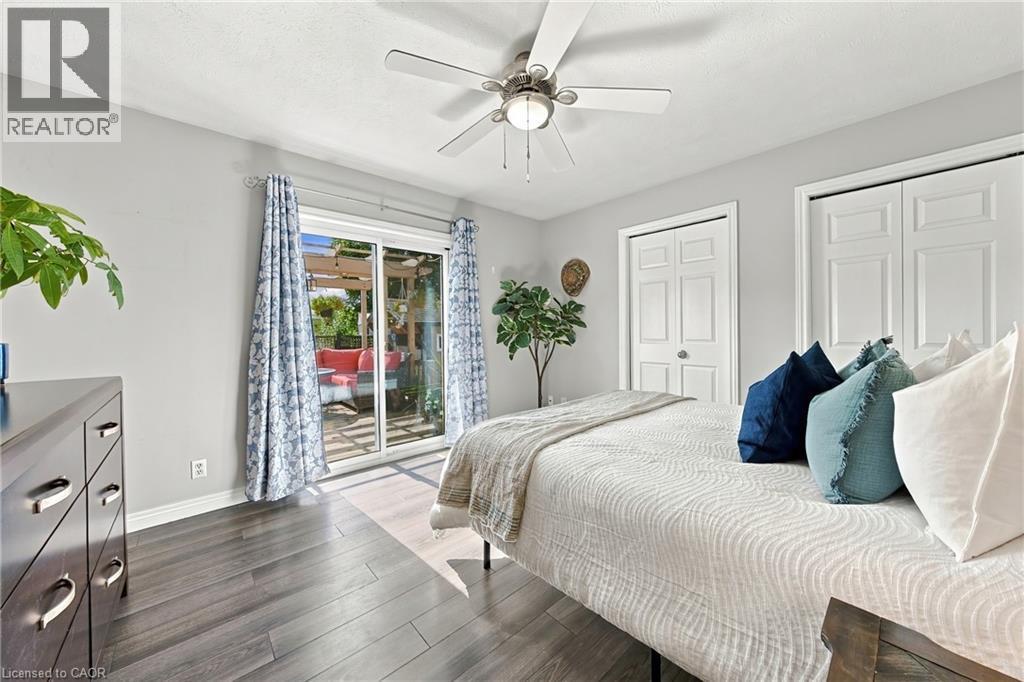 Sliding glass door, wood-finish flooring, ceiling fan with integrated lighting, and white bi-fold closet doors - 915 St George Street, Port Dover, ON