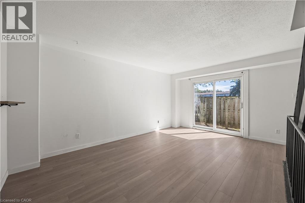 Light wood-finish flooring, white walls, and sliding glass doors with direct outdoor access - 70 Fiddlers Green Road Unit# 74, London, ON