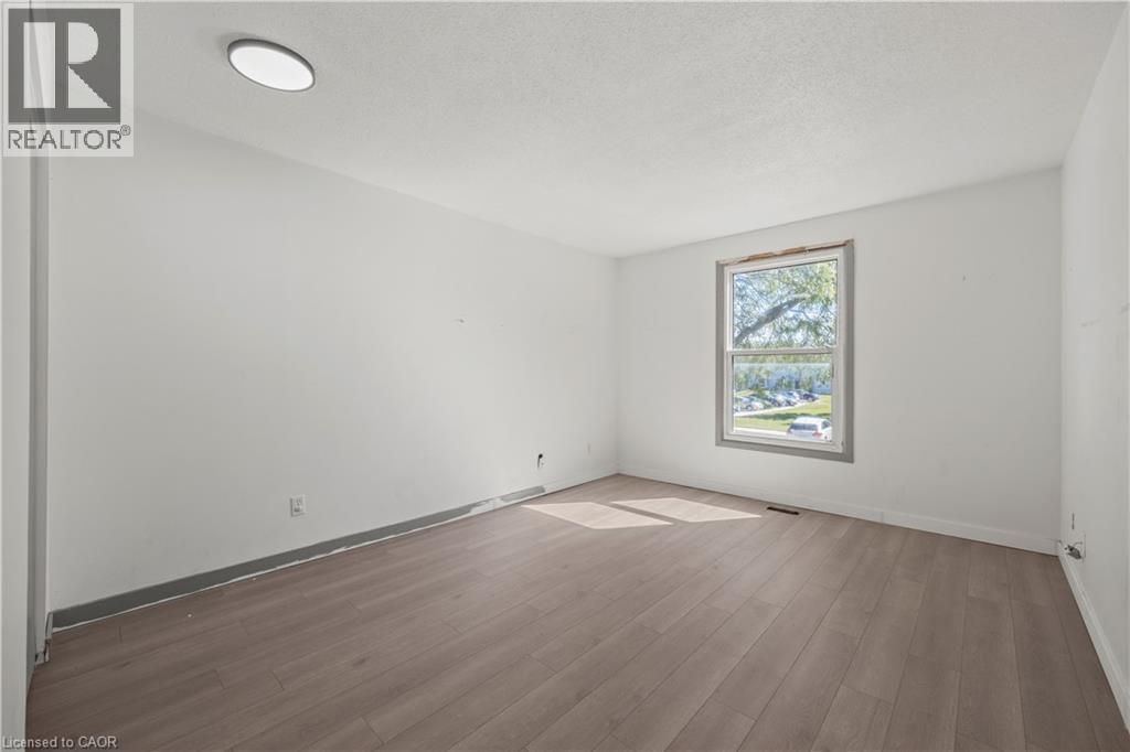 Recessed ceiling light, white painted walls, wood-finish flooring, and a large window - 70 Fiddlers Green Road Unit# 74, London, ON