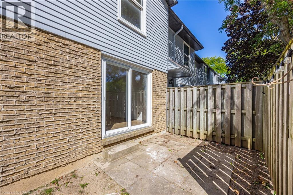 Exterior featuring a brick facade, horizontal siding, and a patio with a privacy fence - 70 Fiddlers Green Road Unit# 74, London, ON