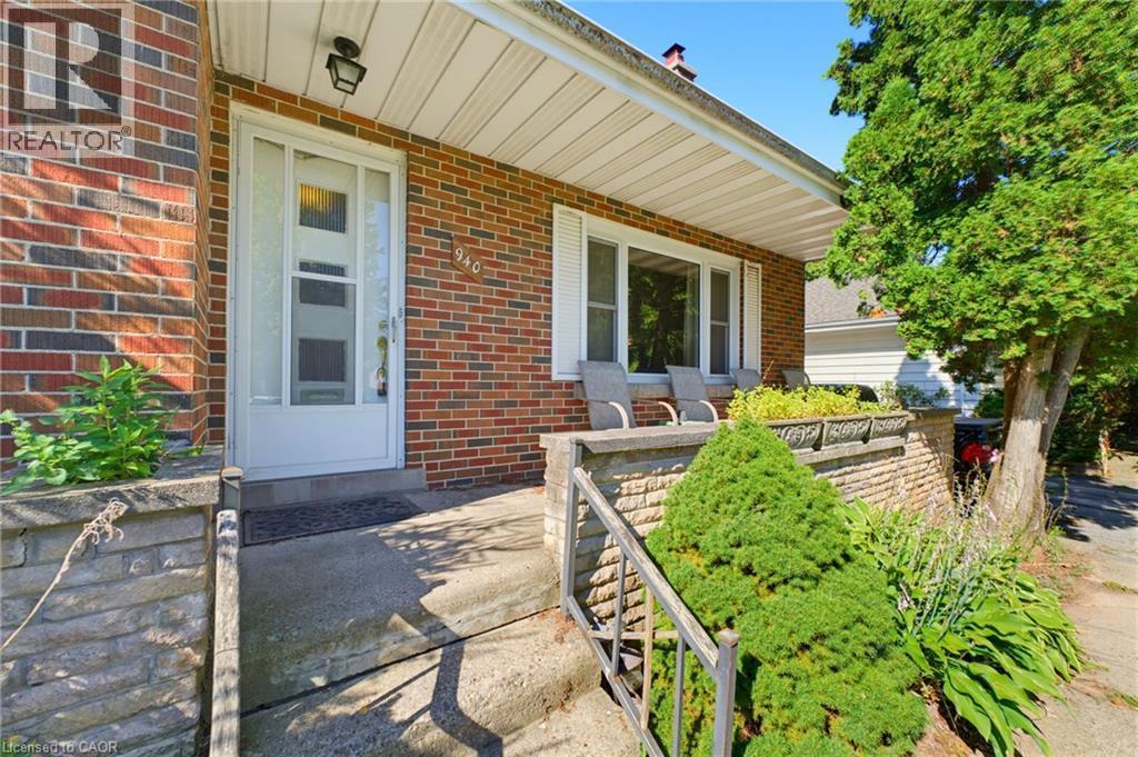 Brick exterior with a covered front porch, white-framed windows, and built-in stone planters - 940 Harvey Place, Halton, ON