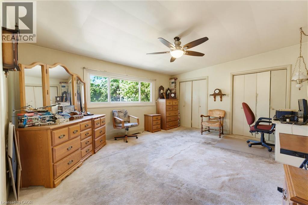 Expansive room featuring a window offering abundant natural light, a ceiling fan with integrated lighting, and two built-in closet systems with bi-fold doors - 940 Harvey Place, Halton, ON