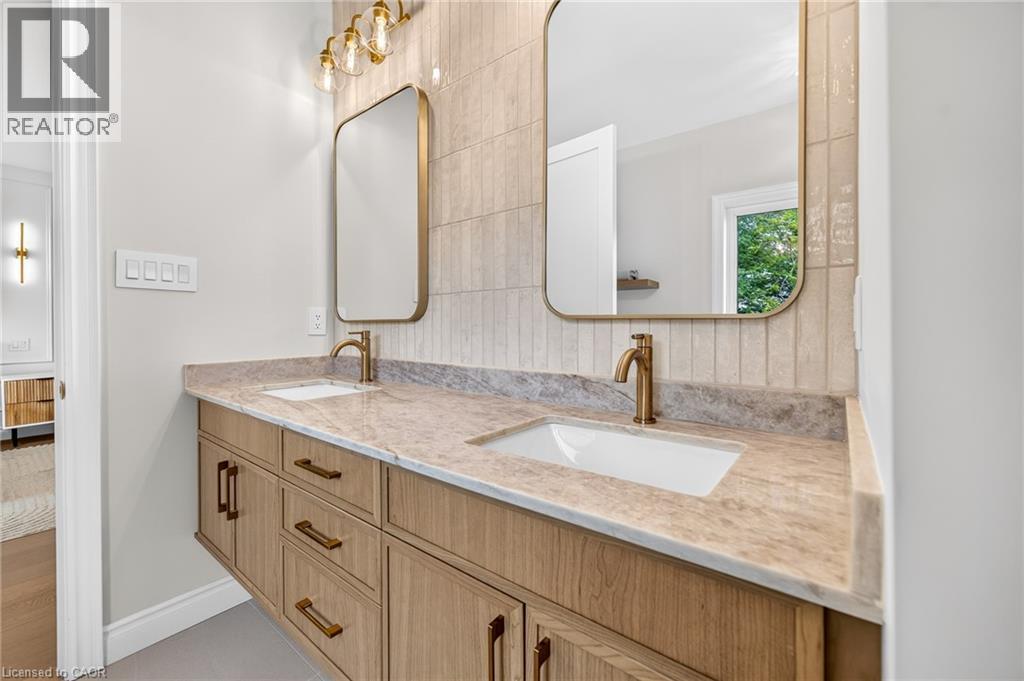 Floating dual vanity with wood-finish cabinetry, integrated sinks, and brass-tone fixtures - 67 Cielo Court, Hamilton, ON