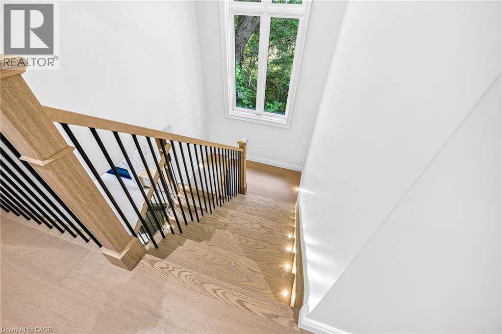 Hardwood stair treads with integrated lighting, wood newel posts, and a black wrought iron spindle railing - 67 Cielo Court, Hamilton, ON
