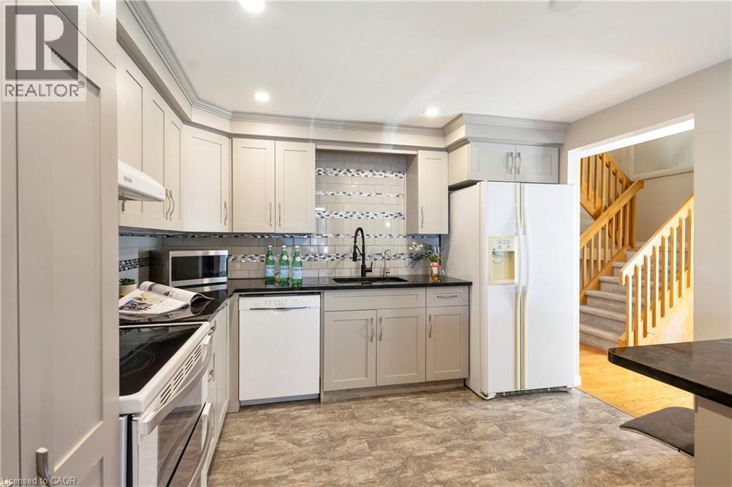 Contemporary kitchen featuring gray cabinetry, black countertops, a mosaic tile backsplash, and a black faucet - 475 Beechwood Drive Unit# 4, Waterloo, ON