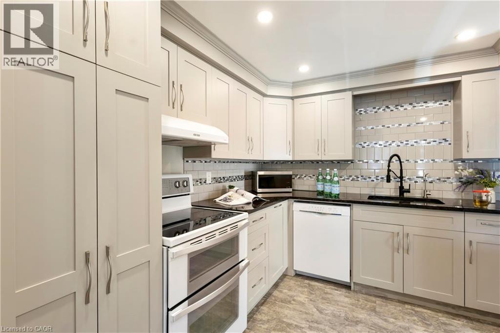 White shaker-style cabinetry with crown molding, solid surface countertops, mosaic tile backsplash, stainless steel appliances, and wood-finish flooring - 475 Beechwood Drive Unit# 4, Waterloo, ON