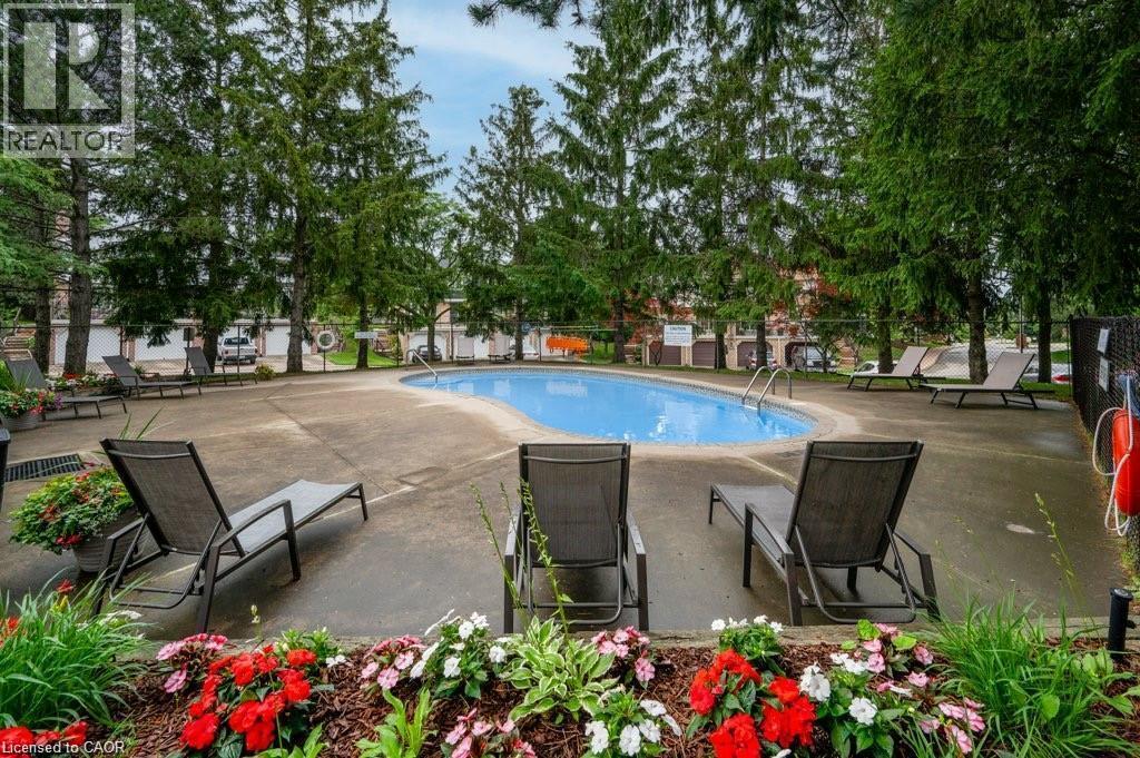 Outdoor swimming pool with concrete surround, mature trees, and landscaping - 475 Beechwood Drive Unit# 4, Waterloo, ON