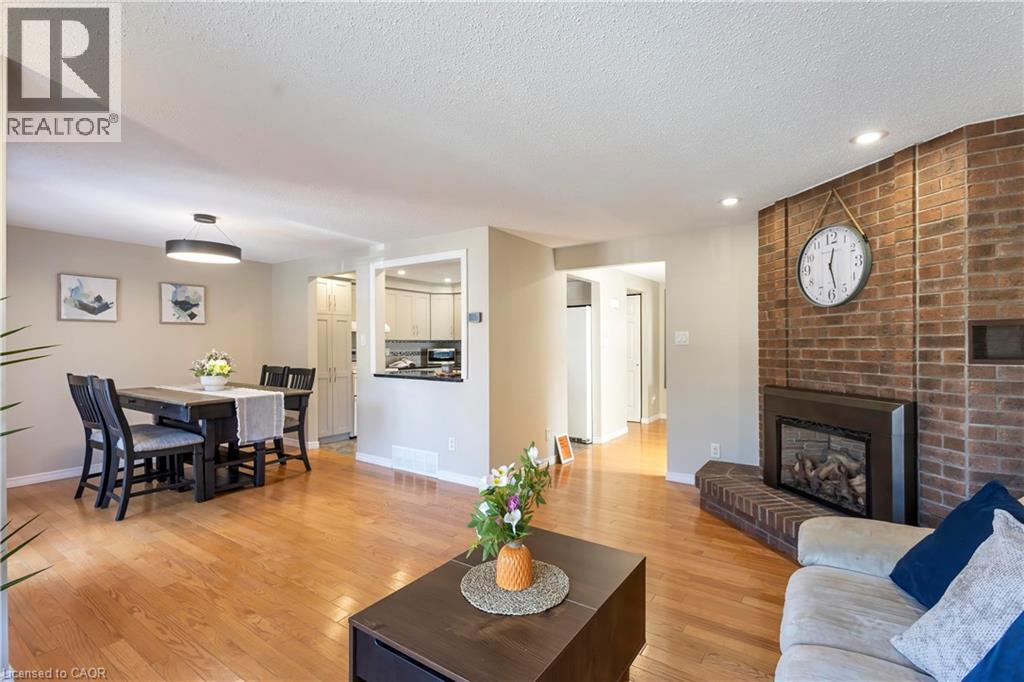 Hardwood-style flooring throughout, brick accent wall with fireplace, recessed lighting, and a kitchen pass-through - 475 Beechwood Drive Unit# 4, Waterloo, ON