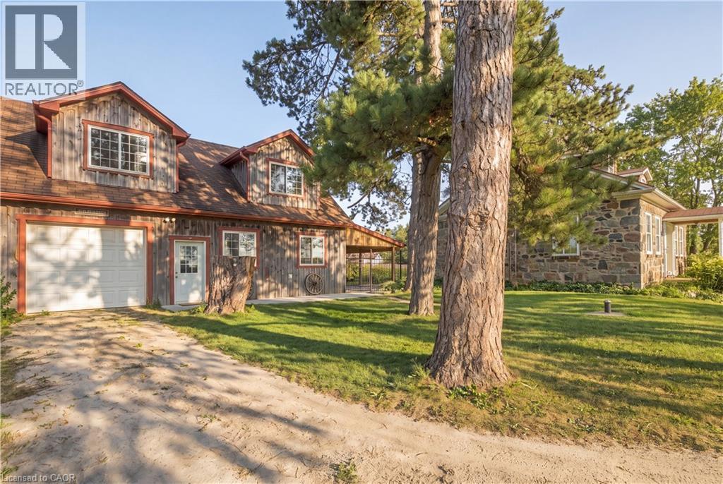 Two-story house with vertical wood siding, attached single-car garage, and a covered porch - 2744 Bleams Road, New Hamburg, ON