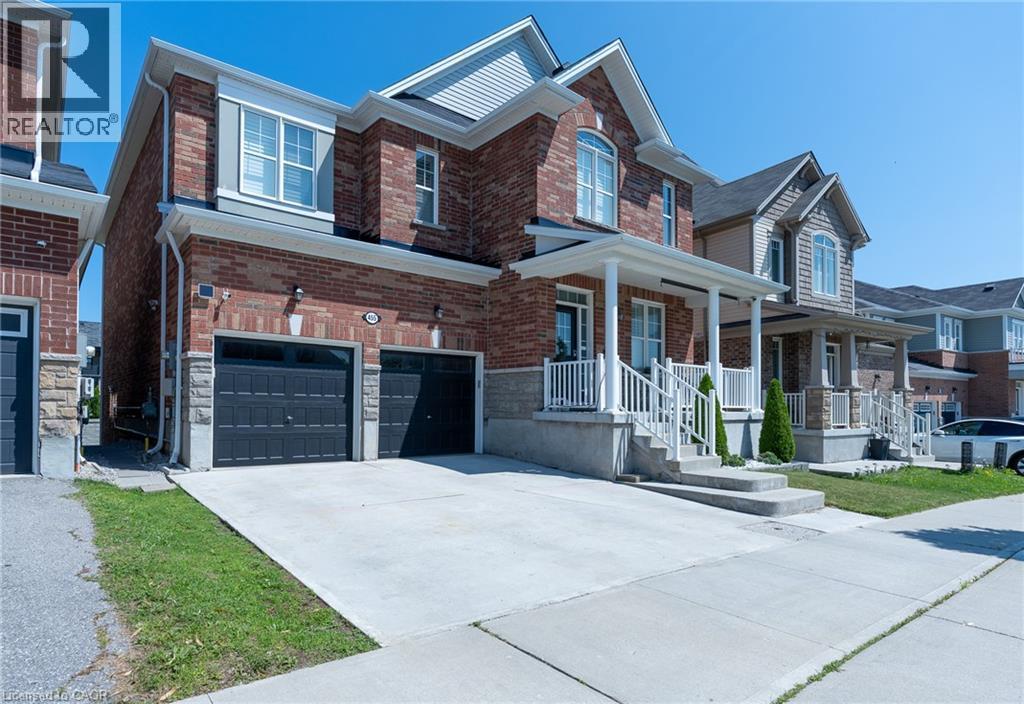 Brick exterior with stone accents, covered front porch, two-car garage, and concrete driveway - 455 Equestrian Way, Cambridge, ON