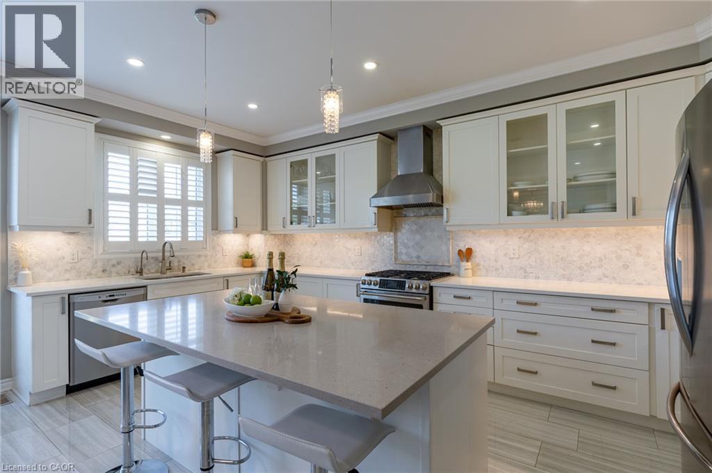 Kitchen featuring a center island, white cabinetry, integrated stainless steel appliances, a tiled backsplash, and recessed lighting - 455 Equestrian Way, Cambridge, ON