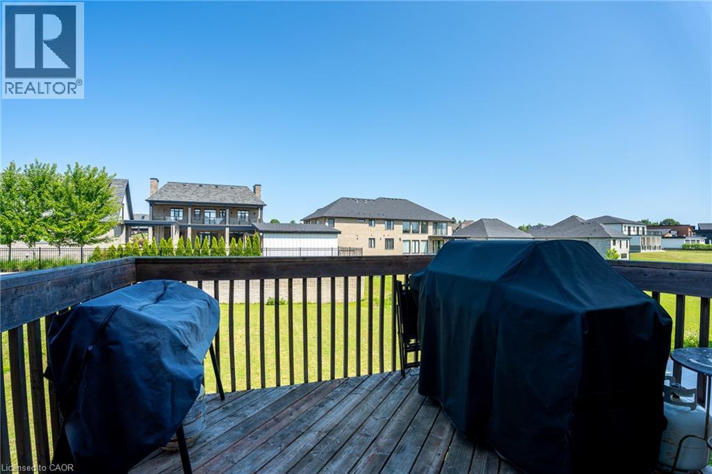Wood deck with dark-stained railing, overlooking a level grassy expanse - 455 Equestrian Way, Cambridge, ON