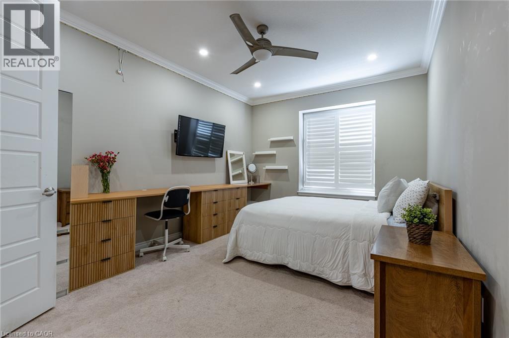 Recessed lighting, crown molding, ceiling fan, window with white plantation shutters, and a built-in wood-finish desk and drawer system - 455 Equestrian Way, Cambridge, ON