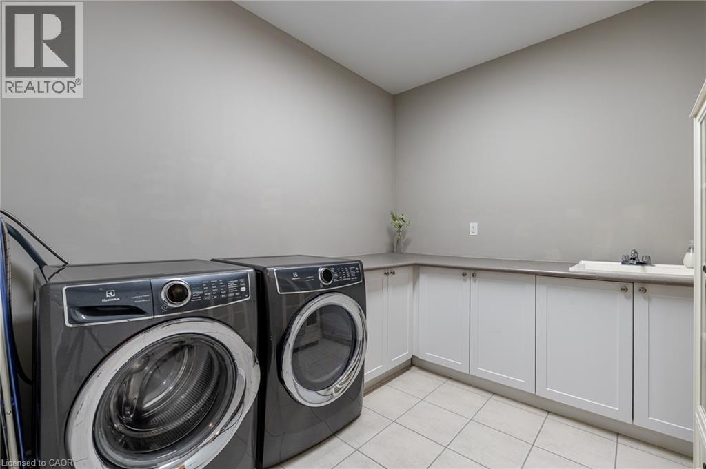 White shaker-style cabinetry with a built-in sink and countertop space, complemented by light-toned tile flooring - 455 Equestrian Way, Cambridge, ON