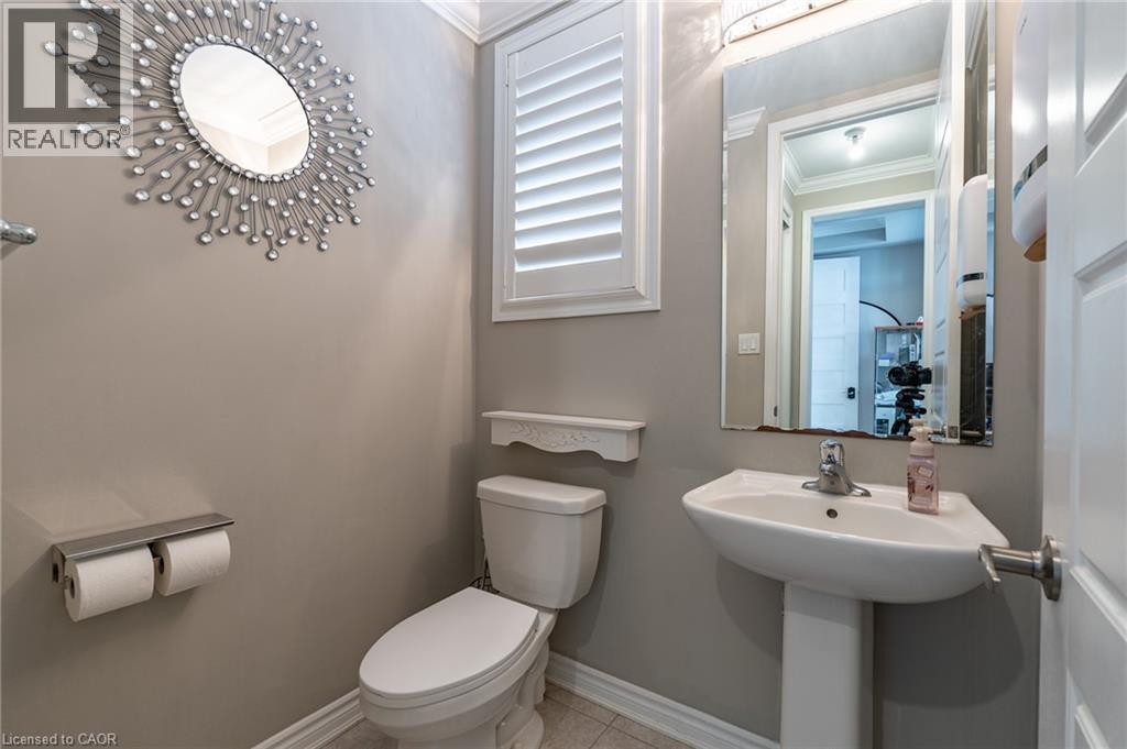 Pedestal sink with chrome faucet, toilet with decorative shelf, and window with plantation shutters - 455 Equestrian Way, Cambridge, ON