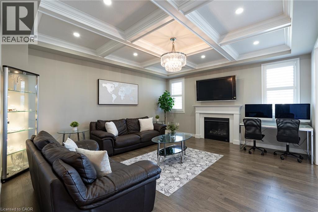 Coffered ceiling with recessed lighting and a chandelier, wood-finish flooring, white fireplace with mantle, and window shutters - 455 Equestrian Way, Cambridge, ON