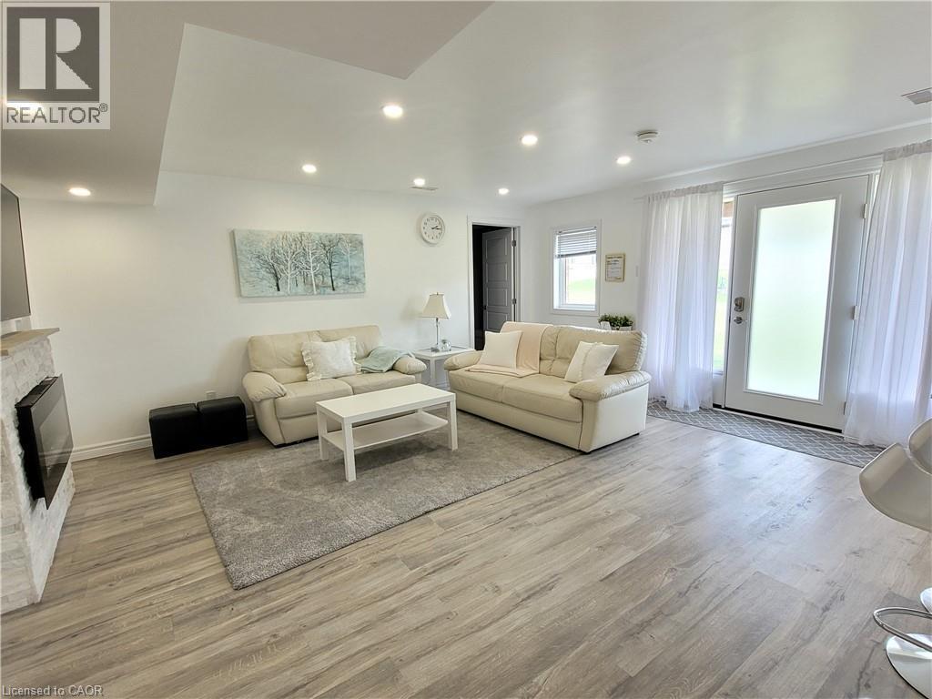 Wood-finish flooring, recessed lighting, white walls, built-in fireplace with stone surround, and sliding glass door with frosted privacy panel - 455 Equestrian Way, Cambridge, ON