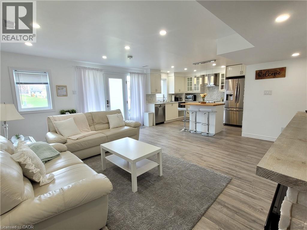 Recessed lighting, wood-finish flooring, white cabinetry, stainless steel appliances, and a kitchen island with seating - 455 Equestrian Way, Cambridge, ON