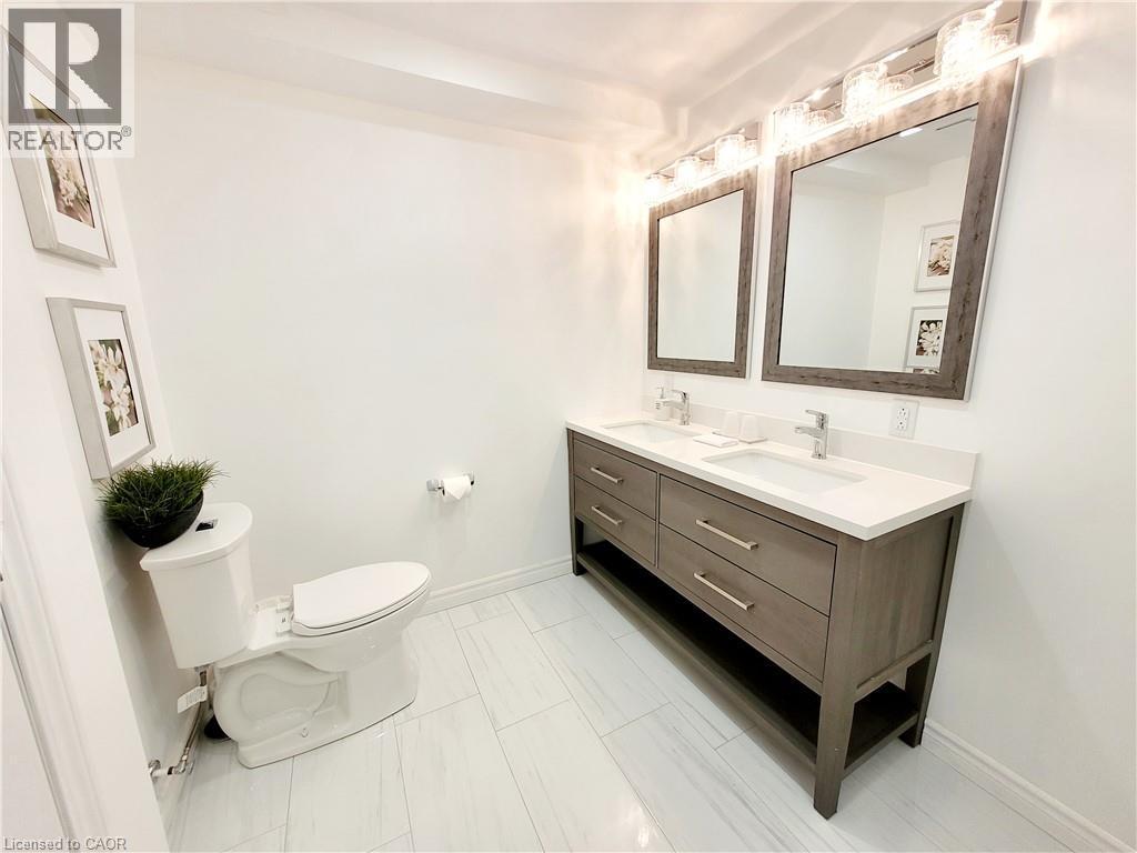 Dual vanity with integrated sinks, white countertop, and dark wood-finish cabinetry - 455 Equestrian Way, Cambridge, ON