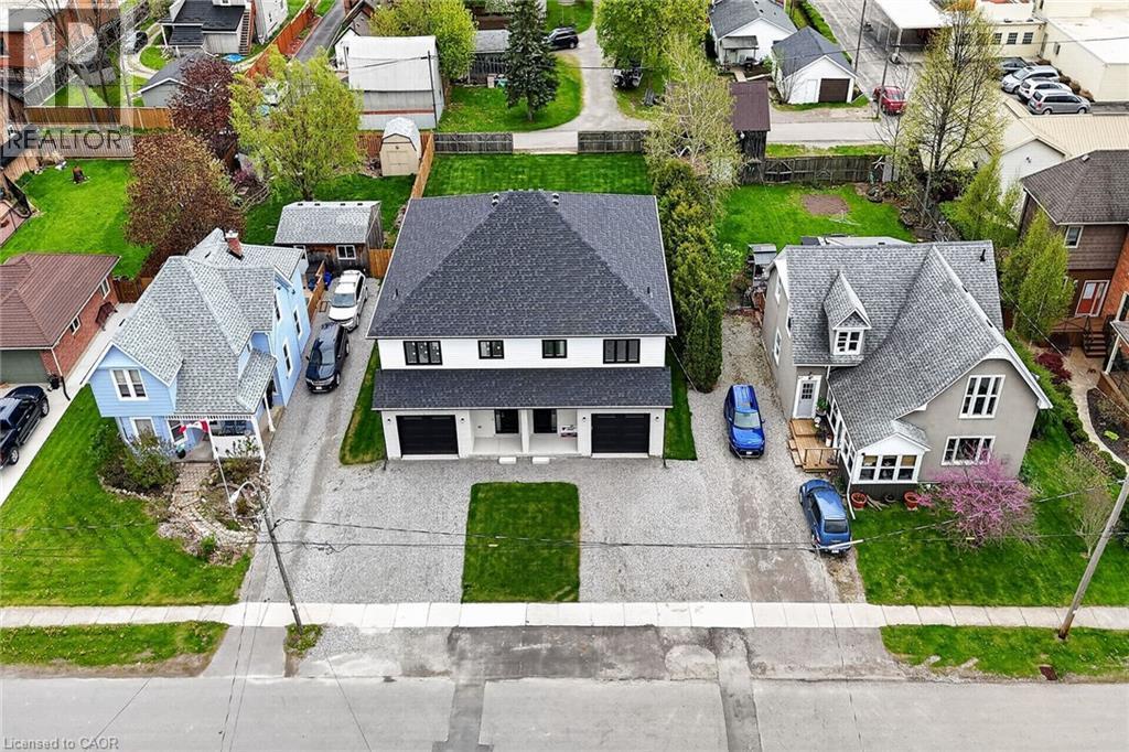 Modern residential building featuring a dark shingle roof, white exterior siding, and two distinct black garage doors - 45A Howard Street, Hagersville, ON