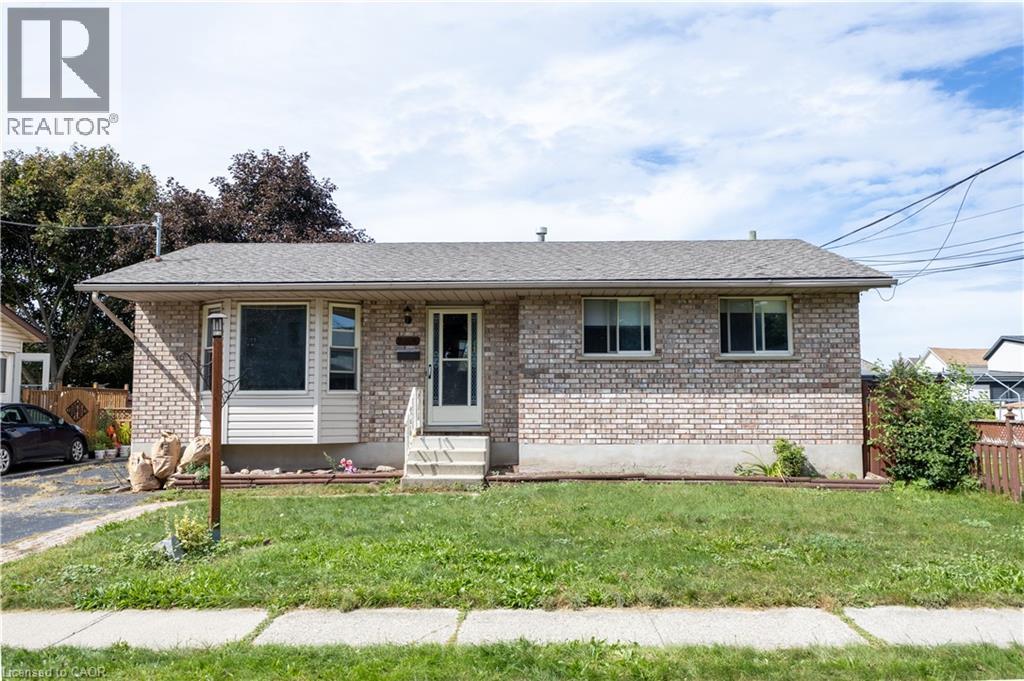 Brick exterior with shingle roofing, featuring a front entry door with storm door, and a concrete pathway - 120 Union Street S, Cambridge, ON