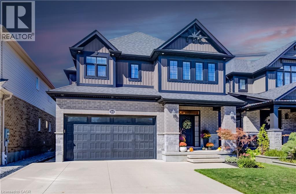 Two-story exterior with a shingled roof, stone and siding facade, covered front porch, integrated garage, and a concrete driveway - 35 Greyhawk Street, Kitchener, ON