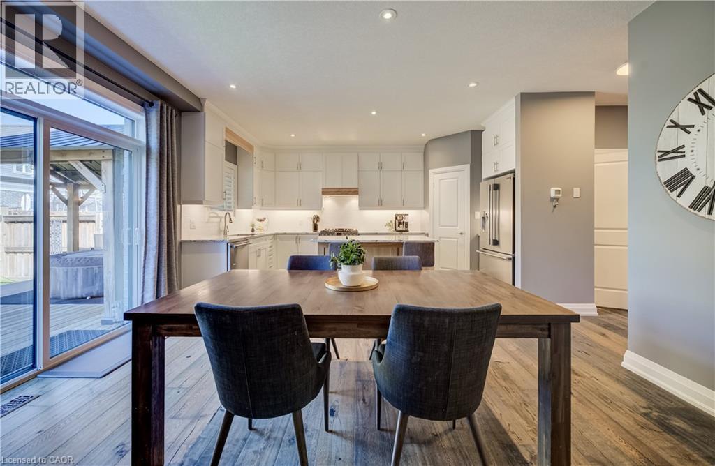 Open-concept layout with wood-finish flooring, white cabinetry, and stainless steel appliances - 35 Greyhawk Street, Kitchener, ON