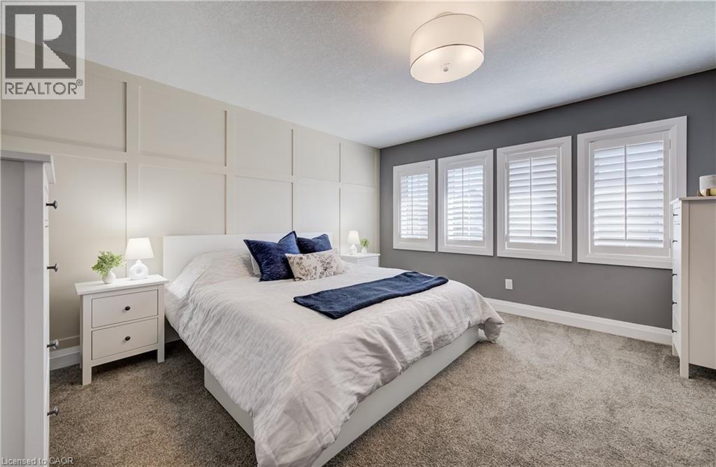 Accent wall with wainscoting, three windows with white shutters, ceiling-mounted light fixture, and neutral carpet flooring - 35 Greyhawk Street, Kitchener, ON