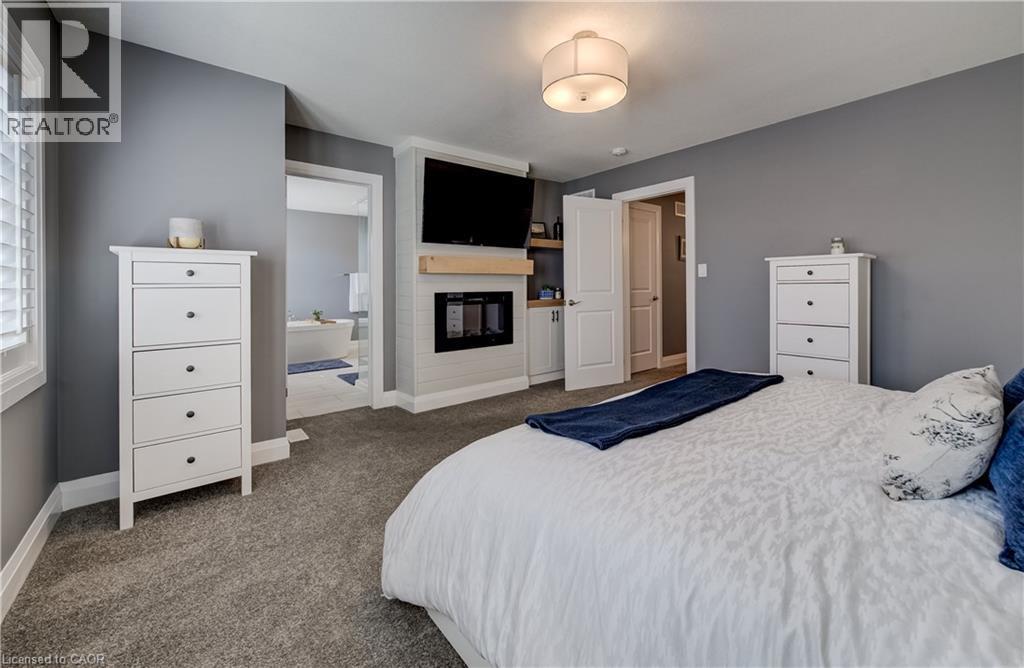 Built-in fireplace with wood-finish mantel, mounted television, and recessed shelving - 35 Greyhawk Street, Kitchener, ON