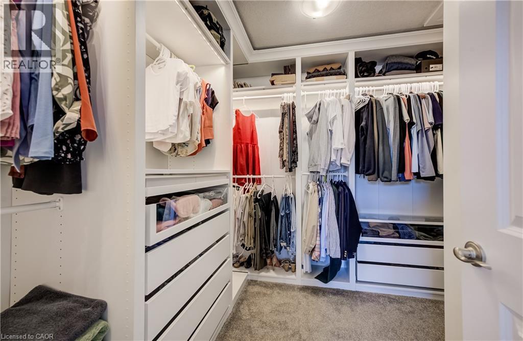 Custom closet system featuring built-in shelving, multiple hanging rods, integrated drawers, and recessed lighting - 35 Greyhawk Street, Kitchener, ON