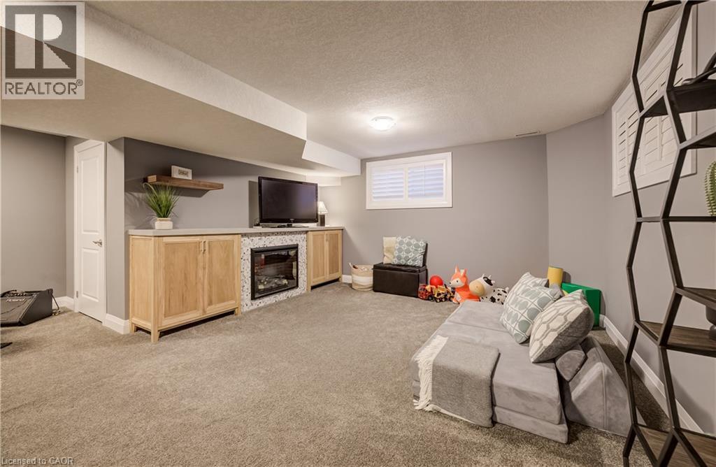 Built-in media console with light wood-finish cabinetry, integrated fireplace, and a floating wood-finish shelf - 35 Greyhawk Street, Kitchener, ON