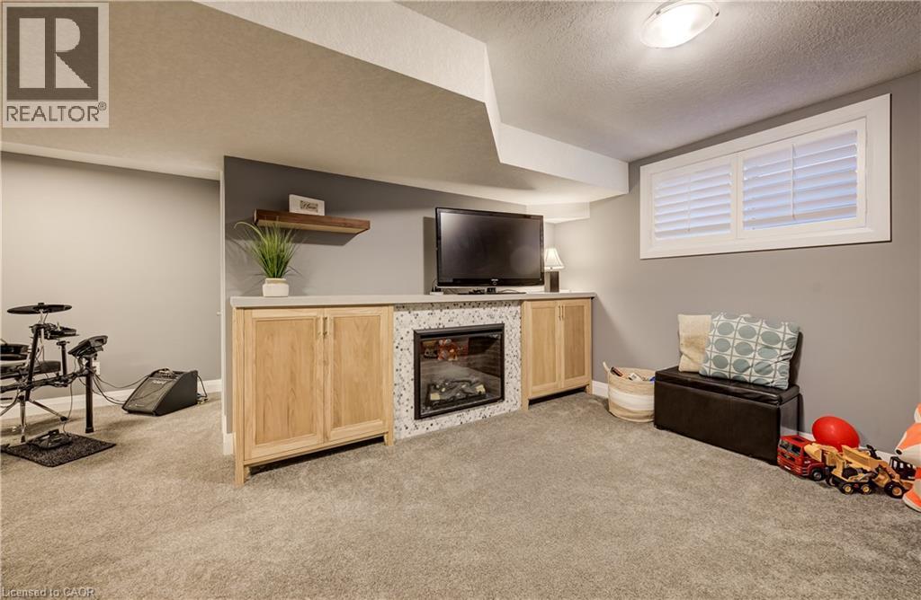 Built-in media console with wood-finish cabinetry, integrated electric fireplace, and countertop - 35 Greyhawk Street, Kitchener, ON
