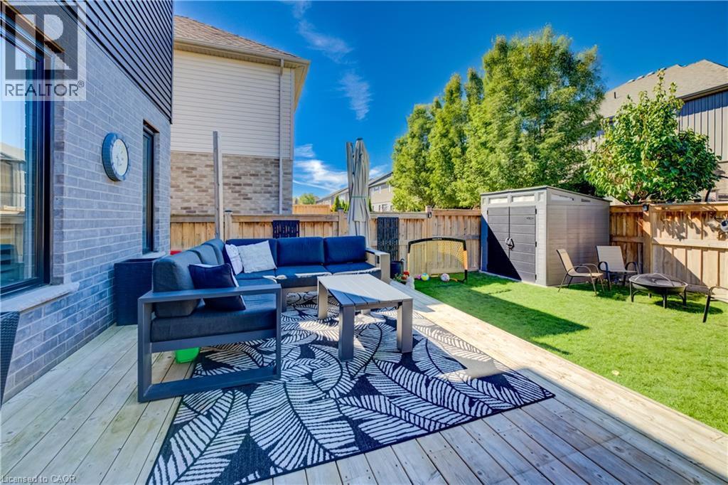 Expansive wood-finish deck with a built-in privacy wall, artificial turf lawn, privacy fencing, and a storage shed - 35 Greyhawk Street, Kitchener, ON