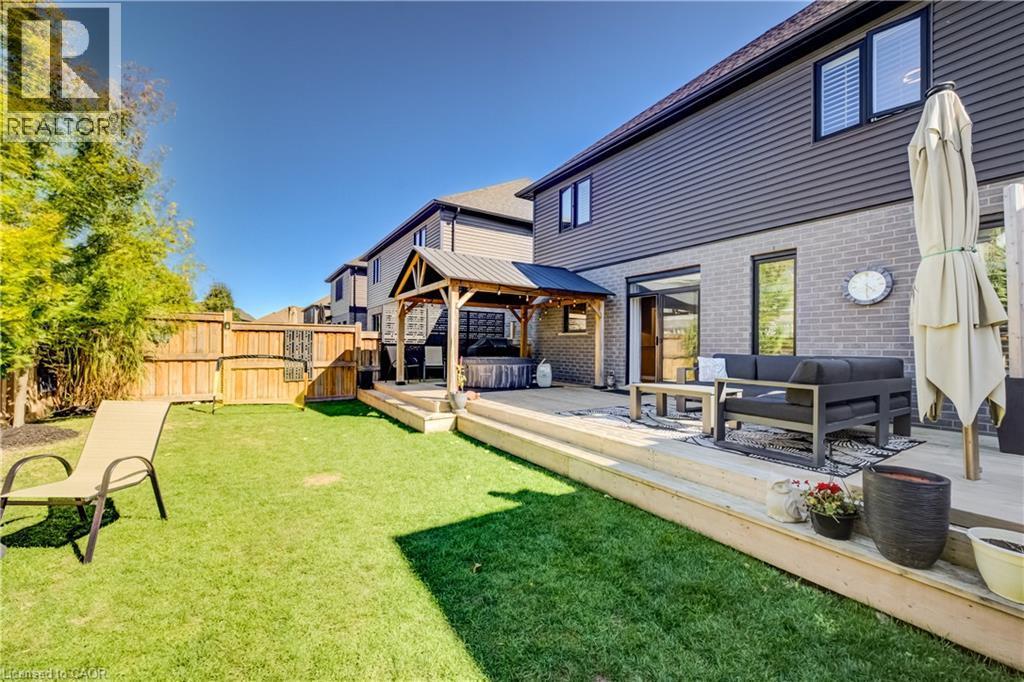 Expansive lawn area with a wooden fence boundary, featuring a multi-level wooden deck - 35 Greyhawk Street, Kitchener, ON