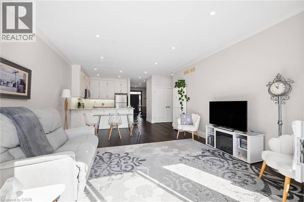 Open-concept living space with dark wood-finish flooring, recessed lighting, and white crown molding - 192 Brewery Street Unit# 18, Baden, ON