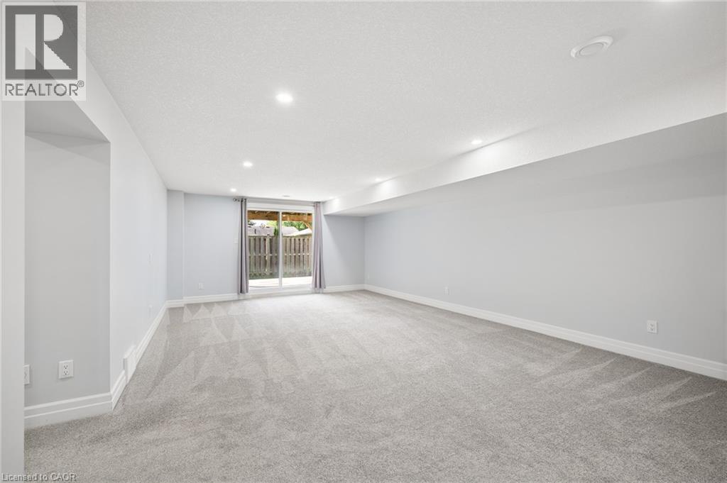 Spacious room featuring light gray carpeting, recessed ceiling lighting, and a sliding glass door - 192 Brewery Street Unit# 18, Baden, ON