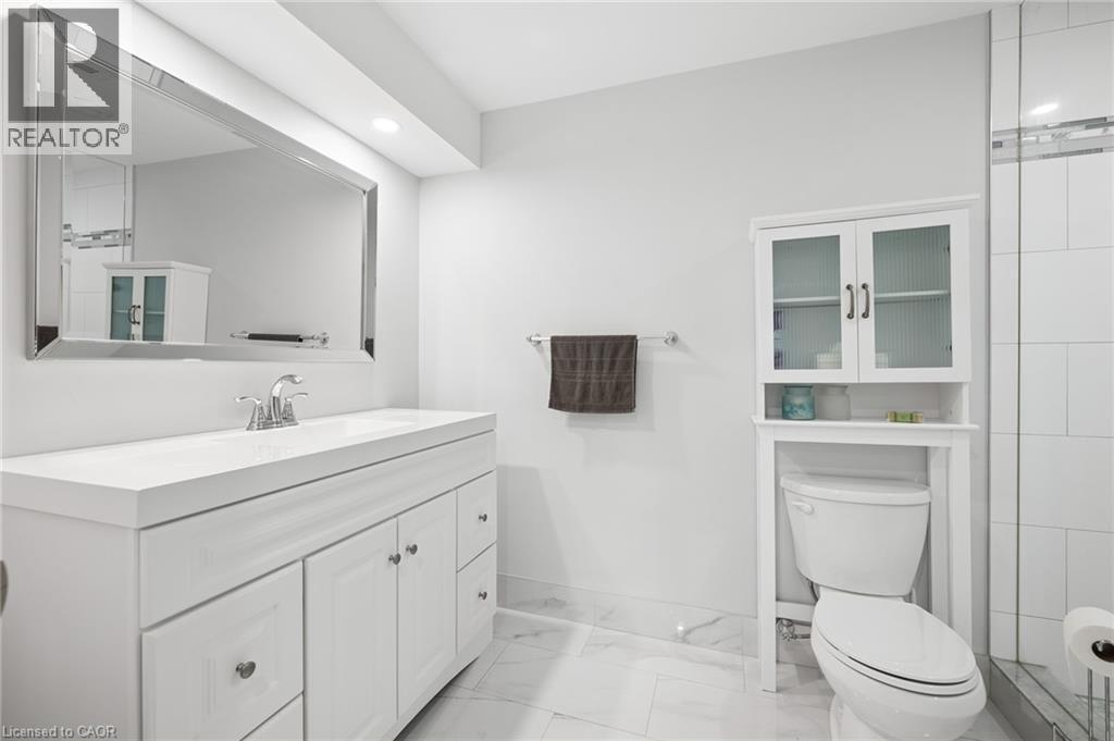 White vanity with integrated sink, rectangular framed mirror, recessed lighting, and over-toilet storage cabinet - 192 Brewery Street Unit# 18, Baden, ON