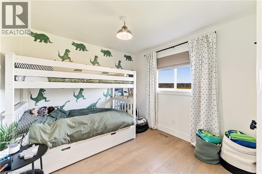 Light wood-finish flooring with a single window featuring a roller shade and decorative curtains - 5367 2 Side Road, Milton, ON