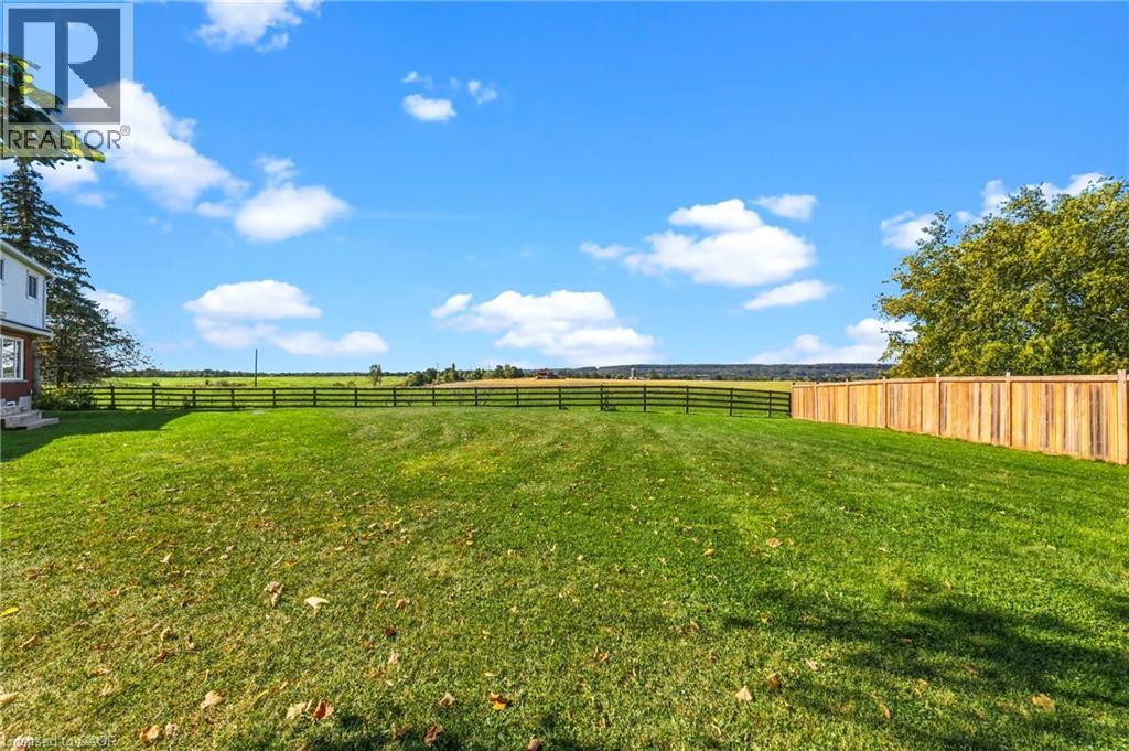 Expansive green space featuring a wood fence, a black wire fence, and mature trees - 5367 2 Side Road, Milton, ON