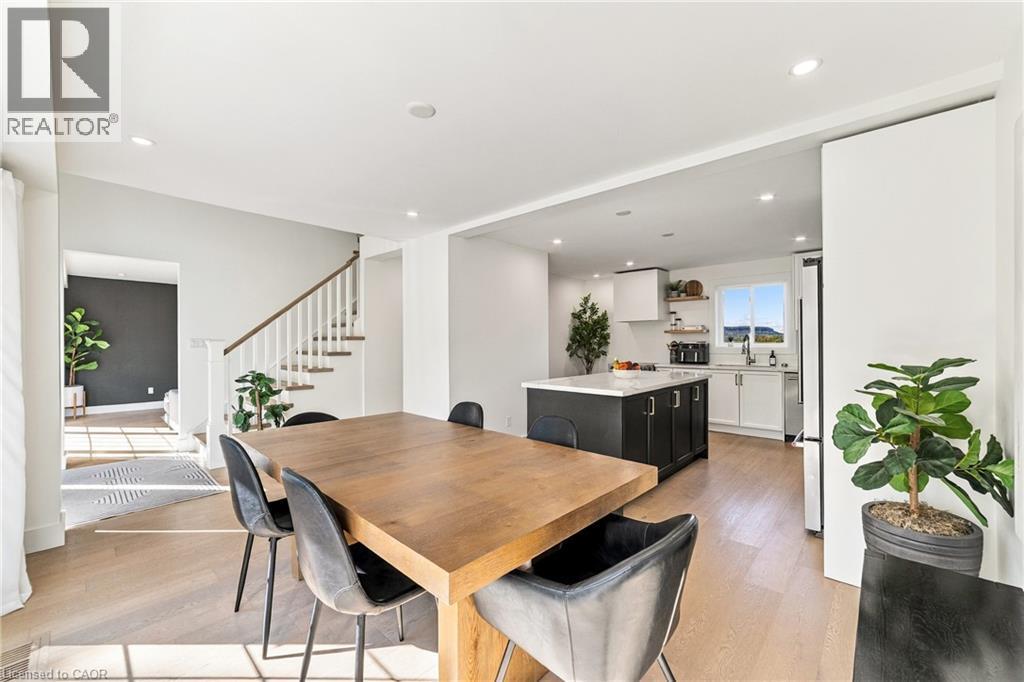 Open-concept living space featuring wood-finish flooring, recessed lighting, and a modern kitchen with a large island - 5367 2 Side Road, Milton, ON