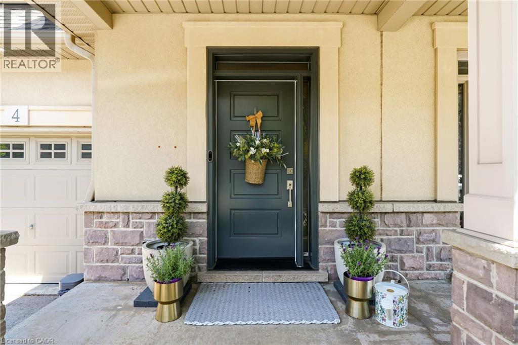 Entry featuring a dark-toned door with a transom, stucco siding, and a stone facade - 5056 New Street Unit# 4, Burlington, ON