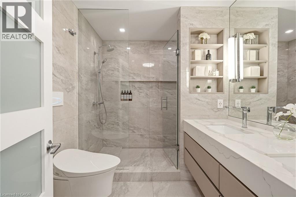 Glass-enclosed shower with a rainfall showerhead, integrated tiled shelving, and a built-in bench - 5056 New Street Unit# 4, Burlington, ON