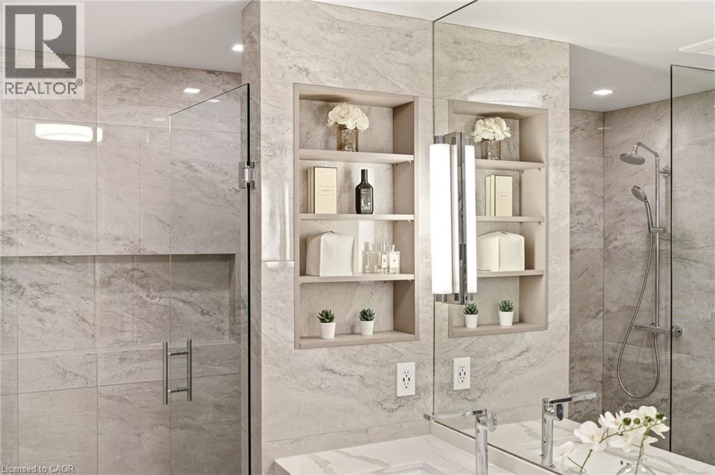 Shower featuring a frameless glass enclosure, recessed storage niche, and a rain showerhead with an additional handheld sprayer - 5056 New Street Unit# 4, Burlington, ON