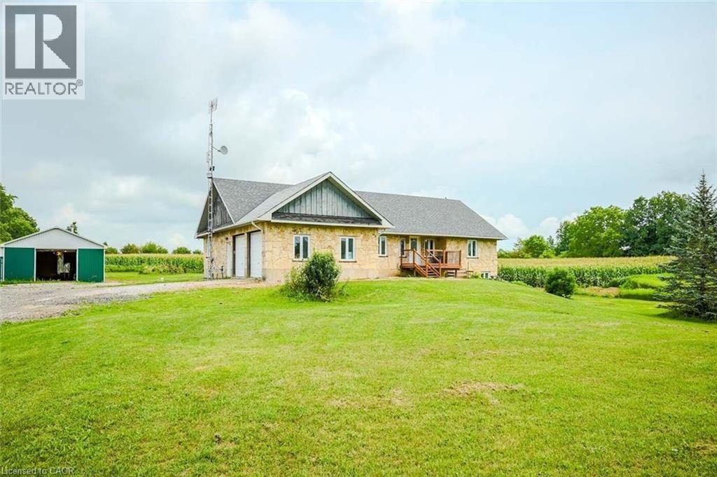 Stone-clad exterior with a gray shingle roof, featuring an attached garage with two white doors - 107 6Th Line Line, Haldimand, ON - Outdoor