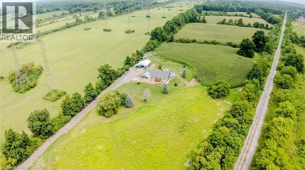 Expansive property featuring verdant fields, established trees, and a residential structure with an attached deck - 107 6Th Line Line, Haldimand, ON - Outdoor With View