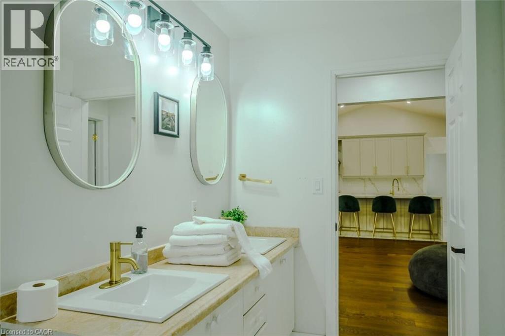 Dual vanity with rectangular undermount sinks, gold-finish fixtures, and wall-mounted lighting - 107 6Th Line Line, Haldimand, ON - Indoor Photo Showing Bathroom