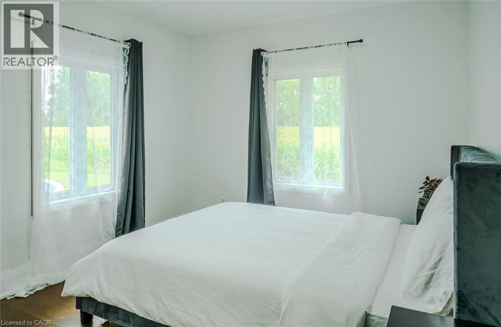 White walls, wood-finish flooring, and multiple windows with trim - 107 6Th Line Line, Haldimand, ON - Indoor Photo Showing Bedroom